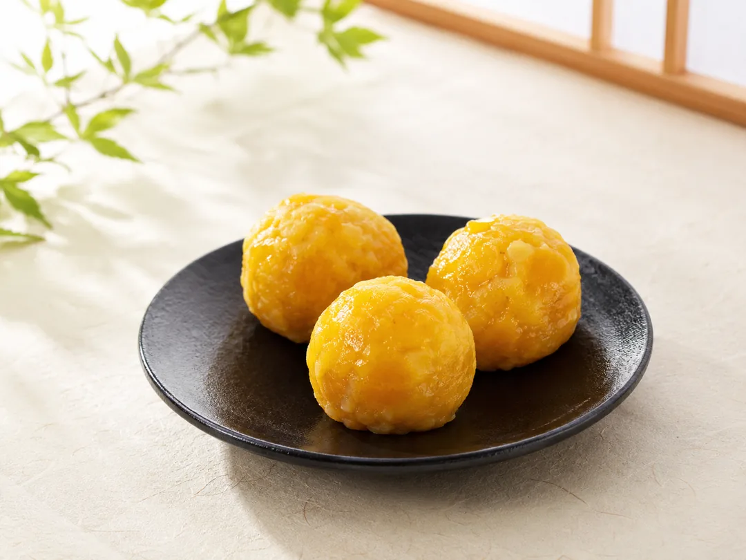 鮮やかな黄金色のさつまいもきんとんを黒い小皿に三つ